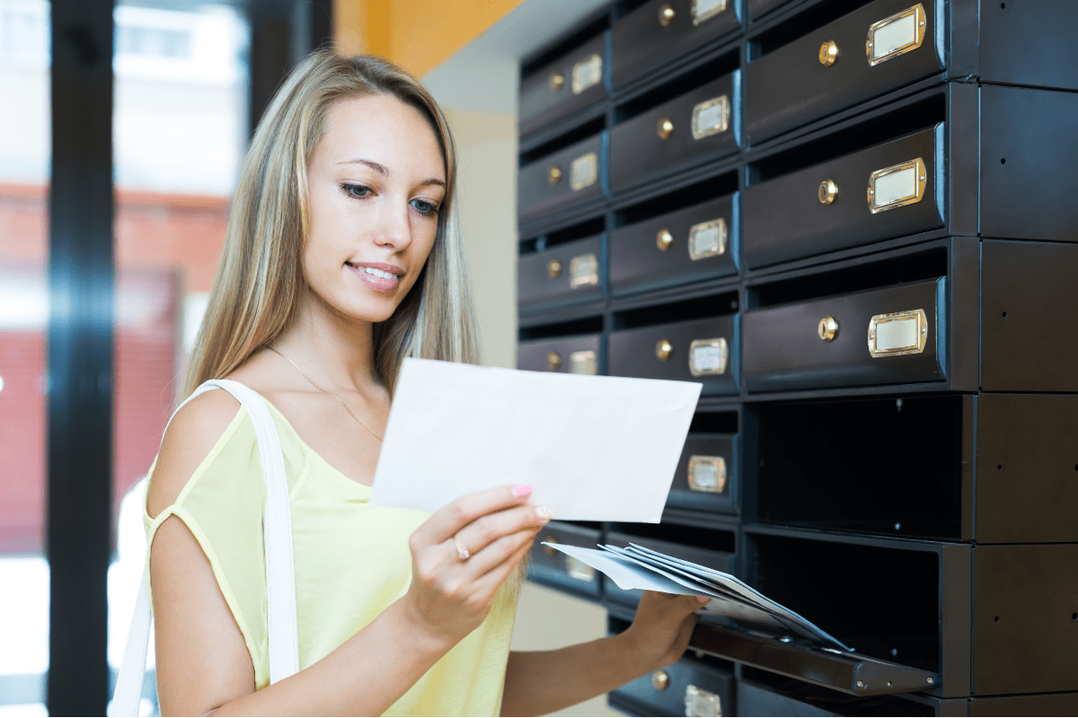 young woman getting mail from mailbox web