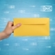 Direct mail performance metrics Hand holding yellow envelope web