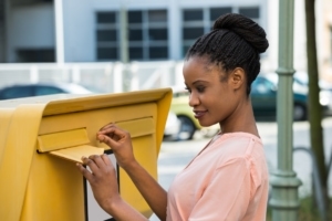 customized mailing lists woman dropping letter in yellow mailbox