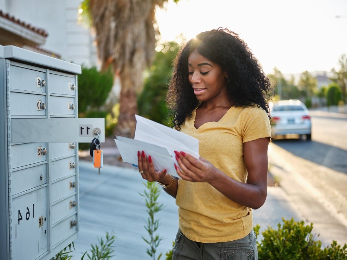 saturation mailing lists woman opening seeing her mail in front of mailbox